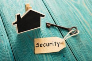 Cardboard Template of house on green table alongside a key with a security label