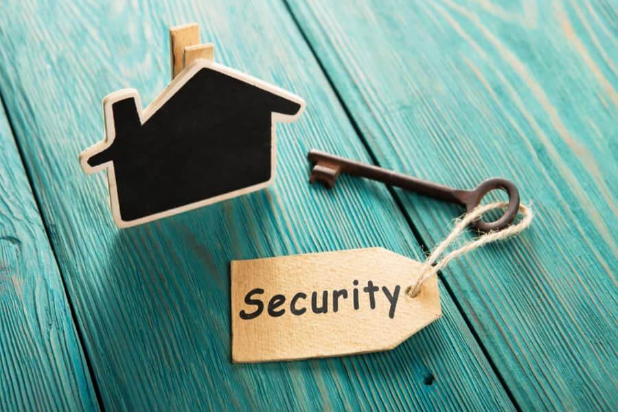 Cardboard Template of house on green table alongside a key with a security label