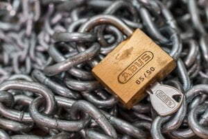 Abus padlock with key laying on top of steel chains to illustrate security hacks for businesses