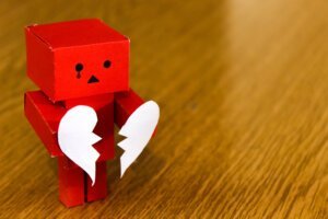 Red cardboard box robot holding a heart split in two to highlight how not to be left broken hearted during Valentines from your home or business security