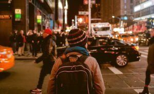 A woman crossing a busy city centre road at night to illustrate how to be threat aware and not afraid in society