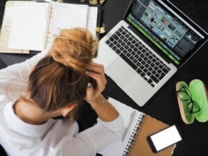 woman with head in hands at her work station depicting the despair she's experiencing from being sexually harrassed in work