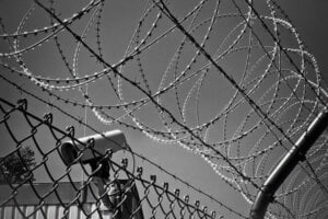 A cctv camera behind a barbed wire fence