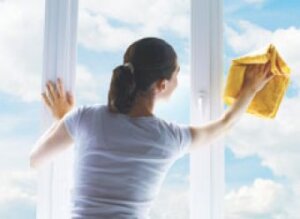 A woman cleaning a 3 paned window to depict giving your business security a spring clean