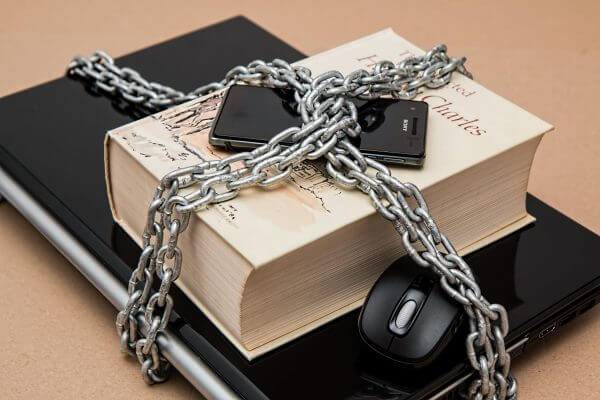 a laptop, book and phone locked in chains