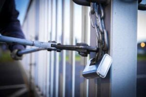 A burgular using a steel cutter to break a locked gate and enter a factory unit