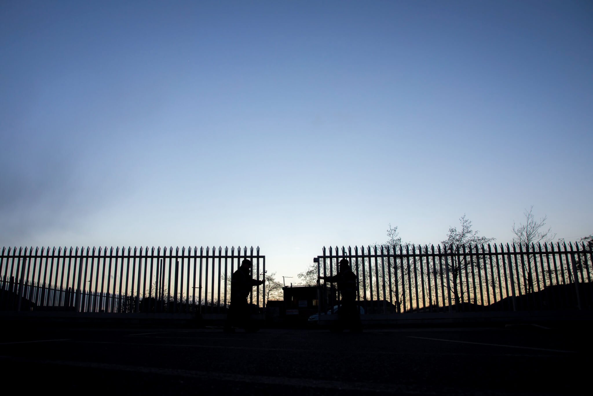 2 mobile security guards closing gates at a manufacturing site on a clear evening night