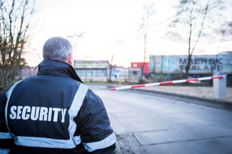 Security guard attending rising arm access barrier at manufacturing site