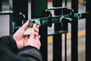 Security guard locking the gates of industrial unit with padlock