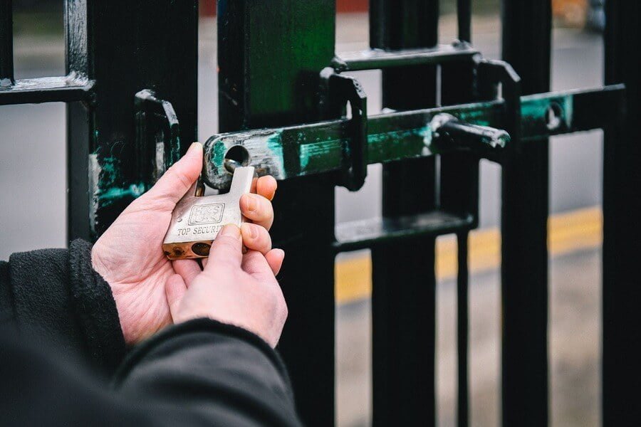 Security guard locking the gates of industrial unit with padlock