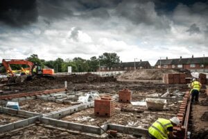 Building site with machinery & bricklayers building walls