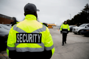 Security guards with high viz jackets patrolling car park on industrial unit in Cardiff