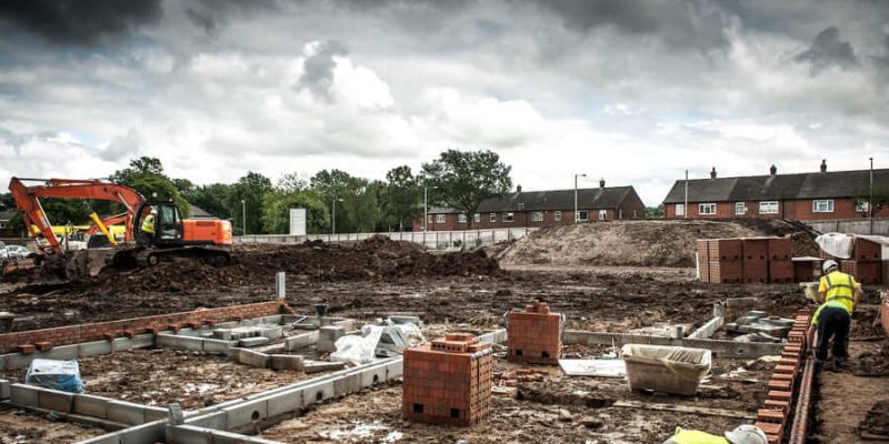 Building site with machinery & bricklayers building walls