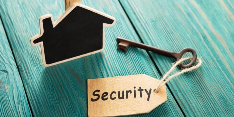 Cardboard Template of house on green table alongside a key with a security label