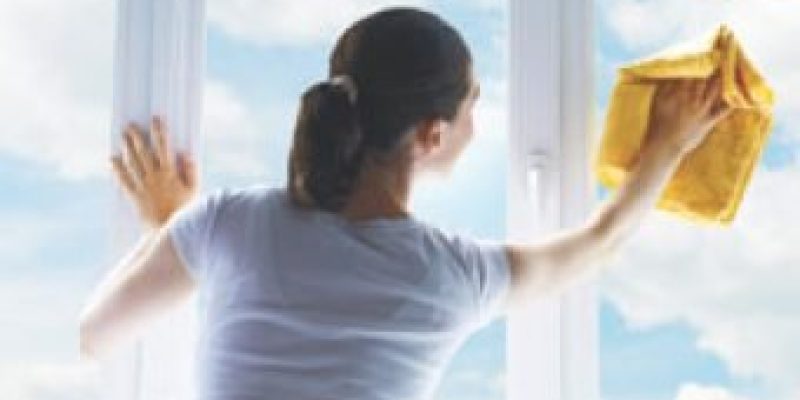 A woman cleaning a 3 paned window to depict giving your business security a spring clean