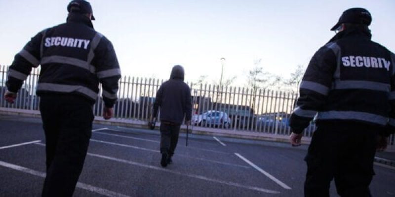 2 Static security guards escorting a hooded criminal holding a steel bar off site