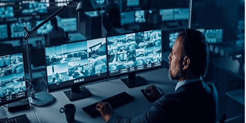 Security guard looking at CCTV monitors in industrial unit Swansea South Wales