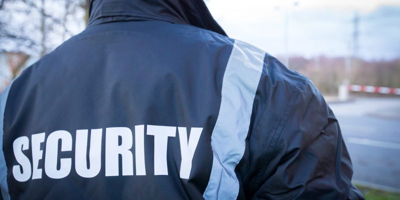 security officer wearing dark blue security coat patrolling security gate at manufacturing site