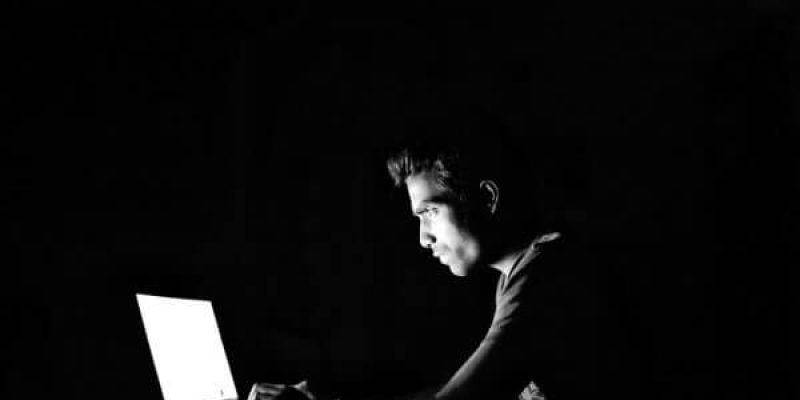 cyber security- a hacker working on his laptop in the dark