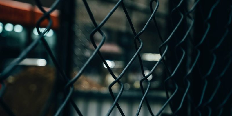 fence with a blurred building in its interior to illustrate perimeter security fencing