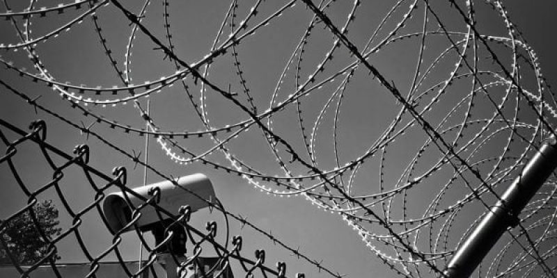 A cctv camera behind a barbed wire fence