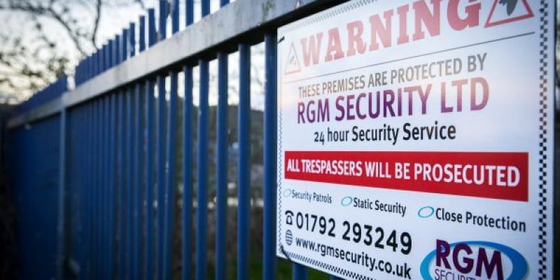A RGM warning security sign located on a perimeter fence of a industrial unit