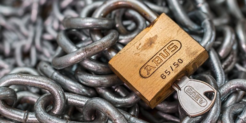 Abus padlock with key laying on top of steel chains to illustrate security hacks for businesses