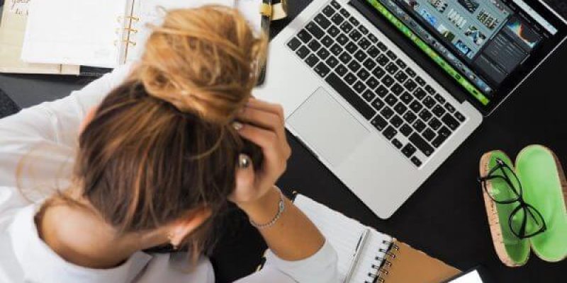 woman with head in hands at her work station depicting the despair she's experiencing from being sexually harrassed in work
