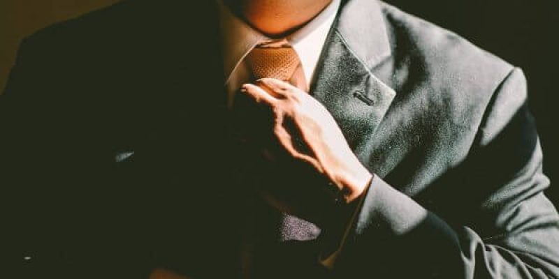 Close up image of a man tightening his suit tie to support how businesses can best understand employee theft and how to combat it