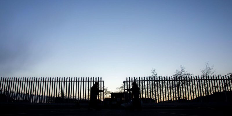 2 static security guards closing security gates on site early evening