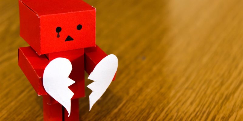 Red cardboard box robot holding a heart split in two to highlight how not to be left broken hearted during Valentines from your home or business security