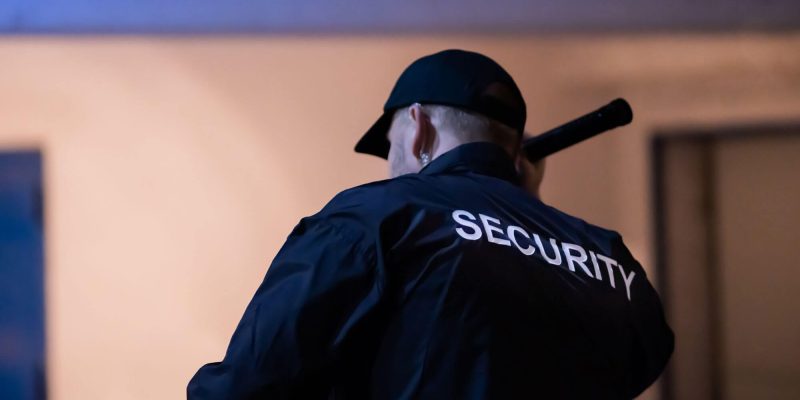 Security guard with torch doing night patrols around factory and recycling plant