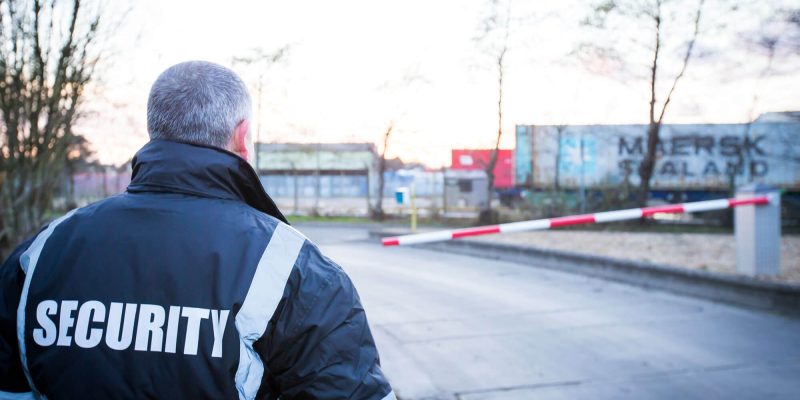 Security guard attending rising arm access barrier at manufacturing site