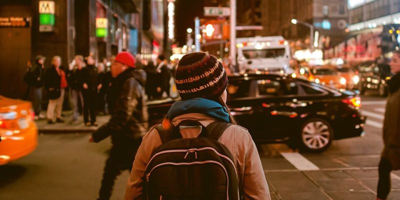 A woman crossing a busy city centre road at night to illustrate how to be threat aware and not afraid in society